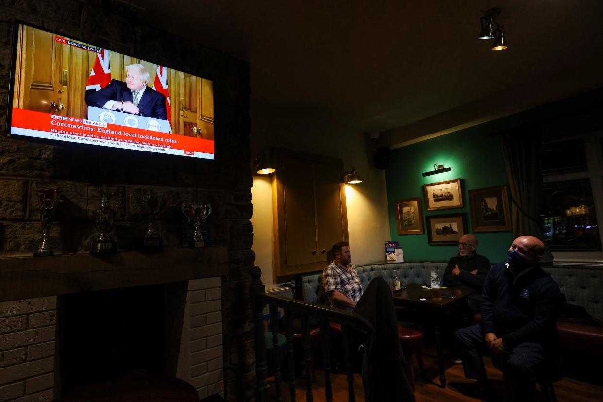 Pub-goers in The Thistleberry, Newcastle-under-Lyme, watch Boris Johnson making a speech on 12 October (Reuters)