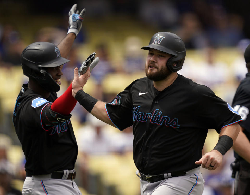 Miami Marlins' Jake Burger, right, is congratulated by Jesus Sanchez, left, after scoring off a double by Bryan De La Cruz during the fourth inning of the first baseball game of a doubleheader against the Los Angeles Dodgers, Saturday, Aug. 19, 2023, in Los Angeles. (AP Photo/Ryan Sun)
