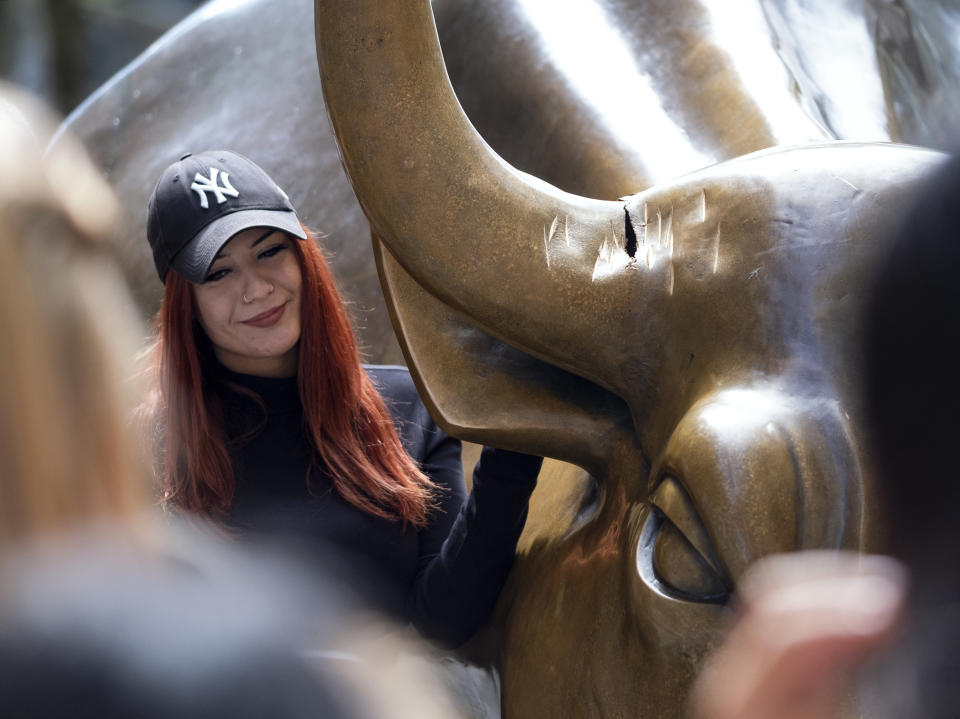 A visitor at the popular lower Manhattan sculpture "Charging Bull" poses for a photo next to the sculpture's damaged horn Sunday, Sept. 12, 2019, in New York. A man was arrested Saturday afternoon for damaging the iconic Wall Street Charging Bull statue with an object resembling a banjo, local media reported. (AP Photo/Craig Ruttle)