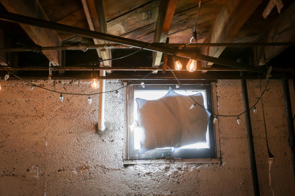 A pillow pinned to a window blocks light and keeps in noise in the basement of Davey Grumbine's home on Wednesday, March 22, 2023. During the day, the basement functions as Grumbine's laundry room, but about once a month, Grumbine hosts concerts in the space.