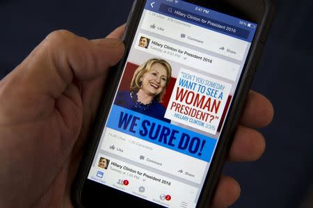 A mobile phone shows a Facebook page of campaign propaganda to promote Hillary Clinton as president in 2016, in this photo illustration taken April 13, 2015. REUTERS/Mike Segar