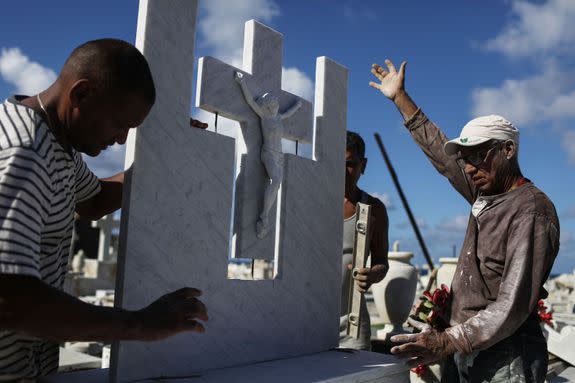 A group of workers repair a gravestone damaged by Hurricane Maria in the immediate aftermath of Hurricane Maria.