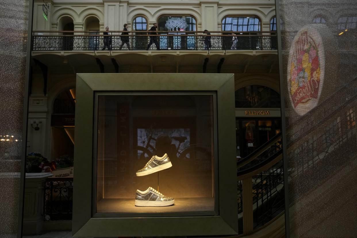 A showcase of the boutique of Jimmy Choo closed due to sanctions in the GUM department store in Moscow, Russia, Tuesday, Aug. 9, 2022. Often, it's hard to tell when stores are closed. At the famous GUM department store lined with shops in Red Square, most of the closed storefronts still had the lights on and a clerk or guard inside. (AP Photo/Alexander Zemlianichenko)