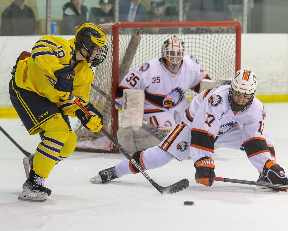 Hartland's LJ Sabala plays the puck in front of Cameron George (17) and goalie Turner England of Birmingham Brother Rice Saturday, Dec. 10, 2022 at Eddie Edgar Ice Arena.