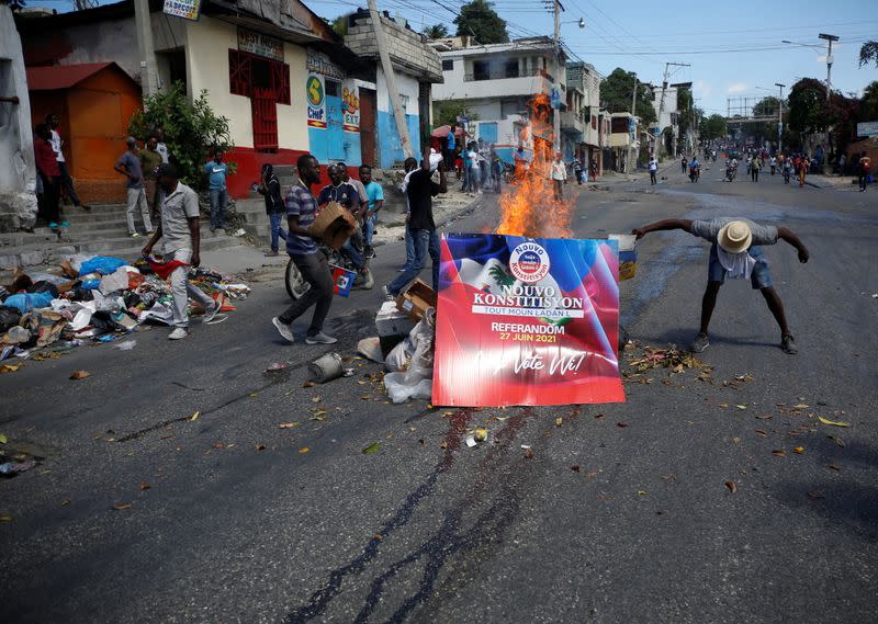 Demonstrators set up a burning barricade using a campaign poster for a referendum on a change of the constitution, during a protest against the government of President Jovenel Moise, in Port-au-Prince