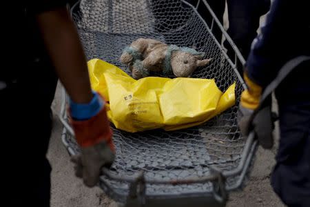 Rescue team members carry a stuffed unicorn and the remains of a mudslide victim towards a temporary morgue, in Santa Catarina Pinula, on the outskirts of Guatemala City, October 5, 2015. REUTERS/Josue Decavele