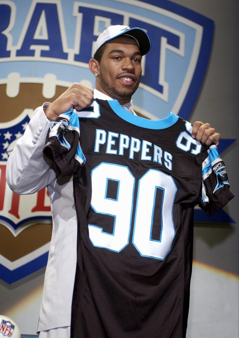 FILE - In this April 20, 2002, file photo, Julius Peppers, of North Carolina, holds up a team jersey after being selected by the Carolina Panthers as their first pick, second overall, in the NFL Draft in New York. After eight years, Peppers is returning home to play for the Panthers. The Panthers agreed to terms on a contract Friday, March 10, 2017, with Peppers, their all-time sack leader, according to a person familiar with the negotiations. The person spoke to The Associated Press on Friday on condition of anonymity because the move can't officially be announced until later in the day. (AP Photo/Ed Betz, File)