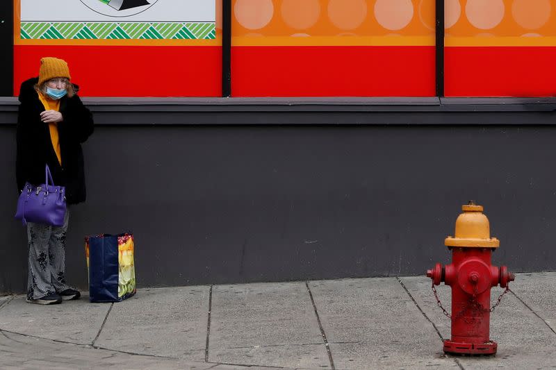 A woman wearing a protective face mask, as the global outbreak of the coronavirus disease (COVID-19) continues, stands outside a discount store in Yonkers, New York