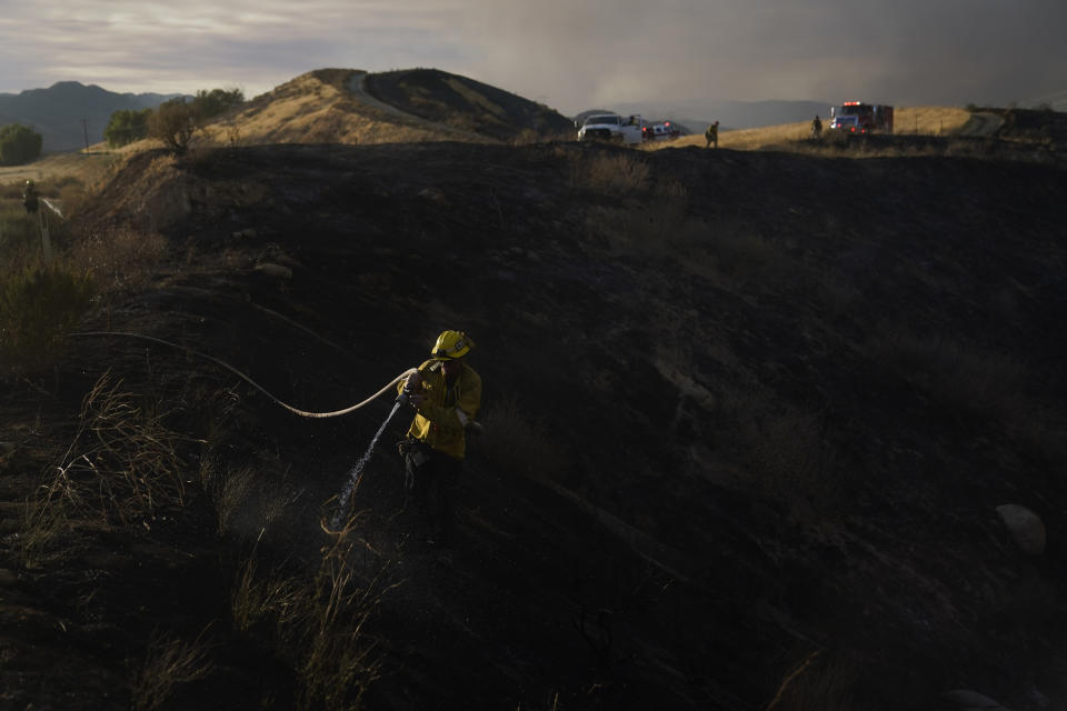 A firefighter hoses down hot spots while battling the Route Fire Wednesday, Aug. 31, 2022, in Castaic, Calif. (AP Photo/Marcio Jose Sanchez)