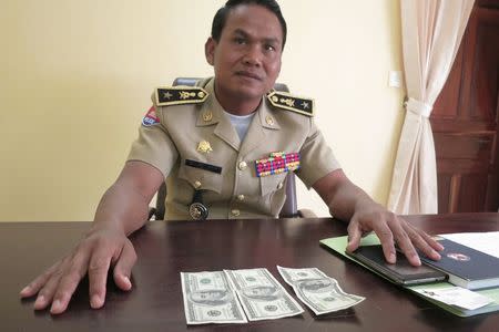 Battambang police chief Brigadier General Sar Theth poses with notes from a seized haul of $7.16 million in counterfeit hundred-dollar bills, in Battambang September 30, 2014. REUTERS/Andrew RC Marshall