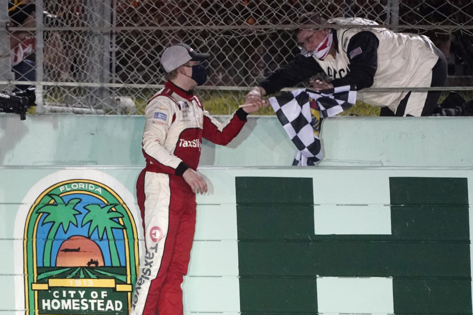 A NASCAR official hands Myatt Snider the checkered flag after Snider won the NASCAR Xfinity Series auto race Saturday, Feb. 27, 2021, at Homestead-Miami Speedway in Homestead, Fla. (AP Photo/Wilfredo Lee)