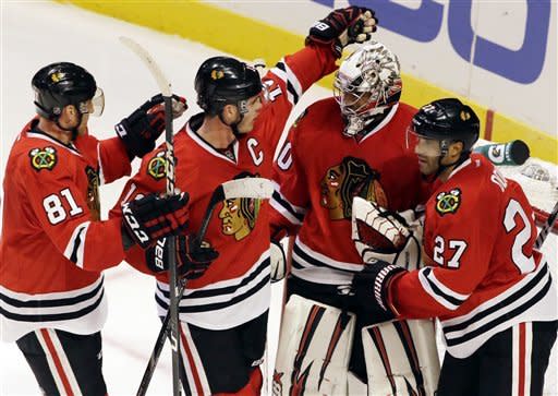 Chicago Blackhawks goalie Ray Emery, second from right, celebrates with Jonathan Toews (19), Marian Hossa (81) and Johnny Oduya (27) after the Blackhawks defeated the San Jose Sharks 2-1 during an NHL hockey game in Chicago, Friday, Feb. 22, 2013. (AP Photo/Nam Y. Huh)