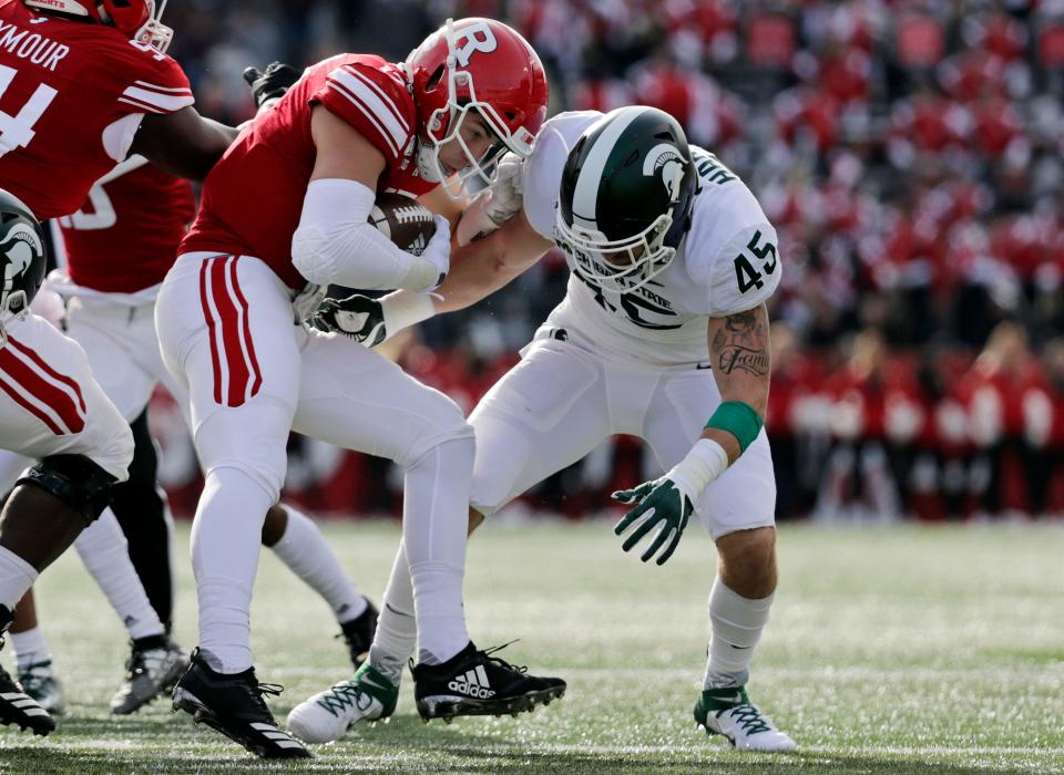 Rutgers quarterback Johnny Langan is tackled by Michigan State linebacker Noah Harvey (45) during the first half of an NCAA college football game Saturday, Nov. 23, 2019, in Piscataway, N.J. (AP Photo/Adam Hunger)