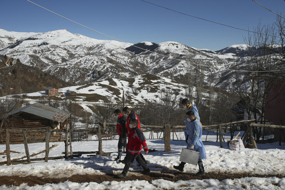 Doctors and health workers of a COVID-19 vaccination team, walk in the isolated village of Gumuslu in the district of Sivas, central Turkey, Friday, Feb. 26, 2021. After traveling snow and ice covered roads, medical workers arrived in the small settlement of 350 people some 140 miles (230 kilometers) from the provincial capital, to vaccinate older villagers. (AP Photo/Emrah Gurel)