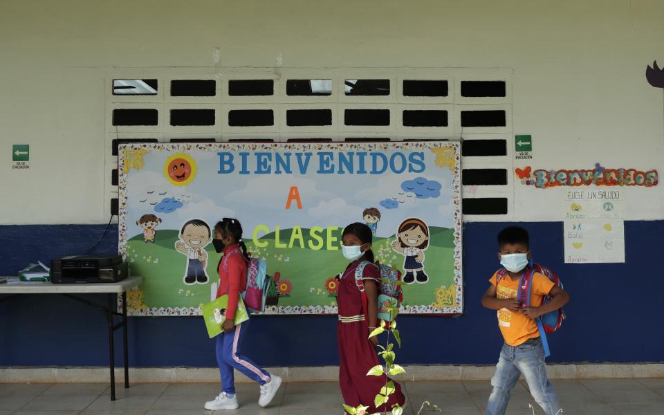 Los estudiantes de primaria salen después de recibir una lección tutorial para reforzar sus clases virtuales en casa, en el centro educativo básico Las Zanguengas en Las Zanguengas, Panamá, el miércoles 24 de marzo de 2021. Al comenzar el nuevo año escolar, aún no se permiten clases presenciales en Panamá. Solo se ha permitido abrir unas pocas escuelas rurales donde las infecciones por COVID-19 son bajas.. (AP Foto/Arnulfo Franco)