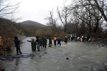 Refugees and migrants cross a river near the Greek-Macedonian border to return to Greece, after an unsuccessful attempt to enter Macedonia, west of the village of Idomeni, Greece, March 15, 2016. REUTERS/Alexandros Avramidis