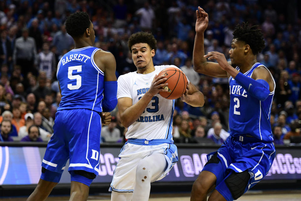 CHARLOTTE, NC - MARCH 15: North Carolina Tar Heels guard Cameron Johnson (13) drives through Duke Blue Devils forward RJ Barrett (5) and Duke Blue Devils forward Cam Reddish (2) during the ACC basketball tournament between the Duke Blue Devils and the North Carolina Tar Heels on March 15, 2019, at the Spectrum Center in Charlotte, NC. (Photo by William Howard/Icon Sportswire via Getty Images)