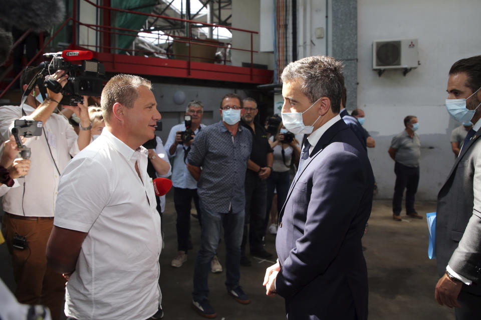 French Interior Minister Gerald Darmanin, right, talks with a bus driver during a visit in Bayonne, southwestern France, Saturday, July 11, 2020. The wife of a French bus driver savagely beaten after he asked four of his passengers to wear face masks aboard his vehicle called Saturday for "exemplary punishment" after he died of his injuries. (AP Photo/Bob Edme)