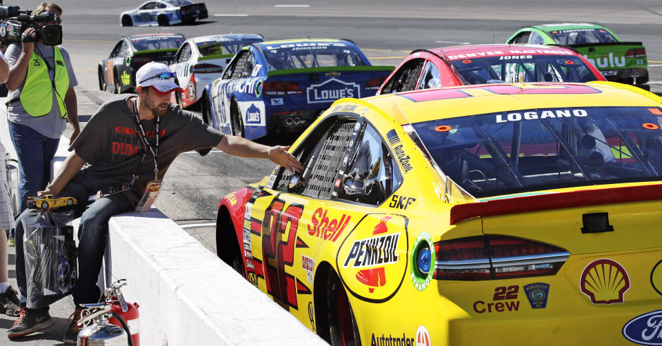 Joey Logano (22) sits parked in car as race fan Jason Wallace, of Ossipee, N.H., reaches over the wall to shake his hand during an afternoon practice for the NASCAR Cup Series 300 auto race at New Hampshire Motor Speedway in Loudon, N.H., Saturday, Sept. 23, 2017. Logano was penalized by officials for inspections violations and forced to sit parked on pit row for the entire practice. (AP Photo/Charles Krupa)