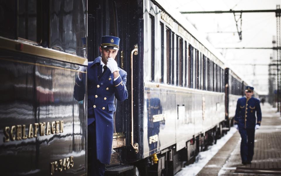 Train conductors in smart blue uniforms prepare for the train to leave the station.