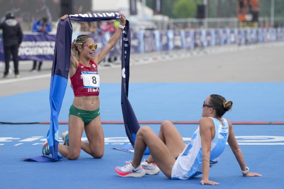 La mexicana Citlali Cristian celebra su triunfo en el maratón femenino, mientras que la argentina Florencia Borelli descansa tras quedar segundo en los Juegos Panamericanos en Santiago, Chile, el domingo 22 de octubre de 2023. (AP Foto/Martín Mejía)