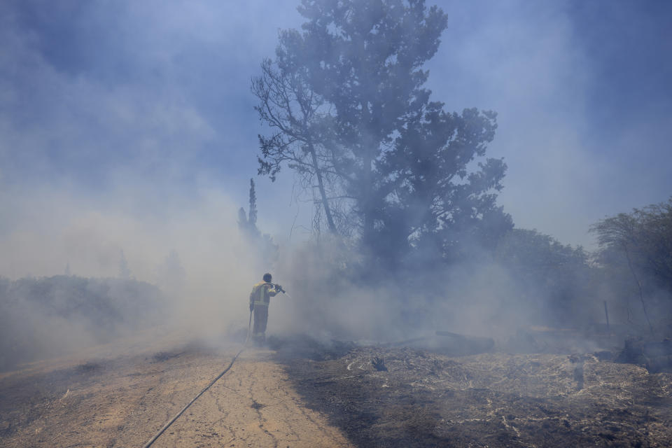 An Israeli firefighter attempts to extinguish a fire caused by an incendiary balloon launched by Palestinians from the Gaza Strip, on the Israel-Gaza border, Israel, Tuesday, June 15, 2021. (AP Photo/Tsafrir Abayov)