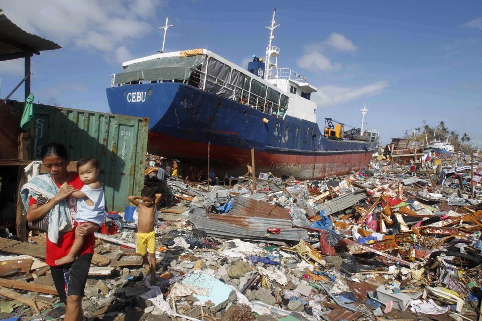 Residents walk past a cargo ship washed ashore four days after super typhoon Haiyan hit Tacloban