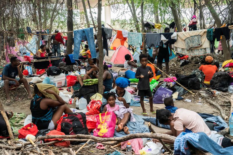 Asylum-seeking migrants wait to be processed near the international bridge in Del Rio, TX