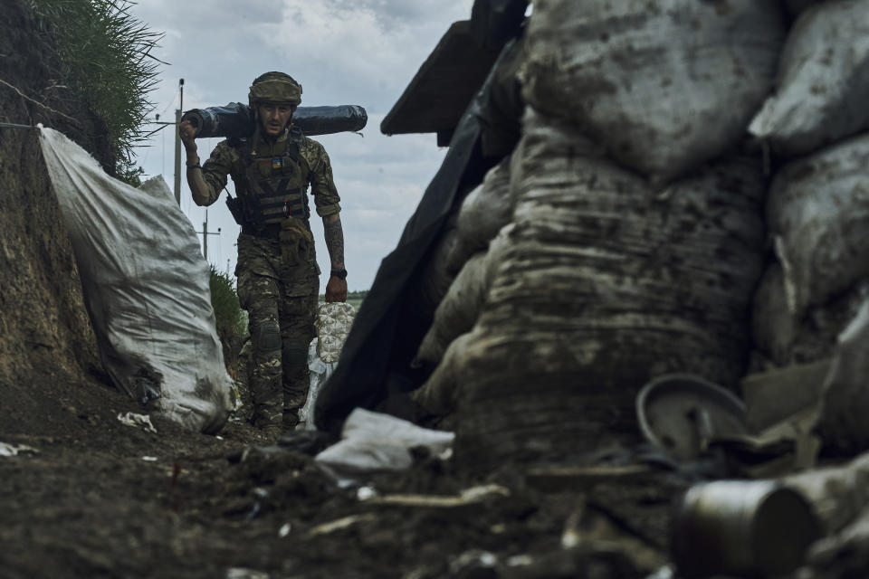 A Ukrainian soldier carries supplies in a trench at the frontline near Bakhmut in the Donetsk region, Ukraine, Monday, May 22, 2023. (AP Photo/Libkos)