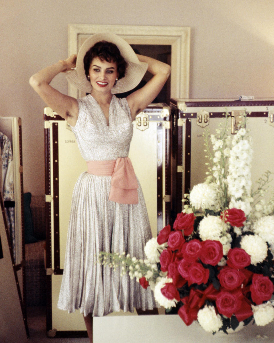 Loren's sleeveless dress and wide-brimmed hat are perfect for a long weekend date night, or even just a walk in the park. Here, she's seen in 1955.