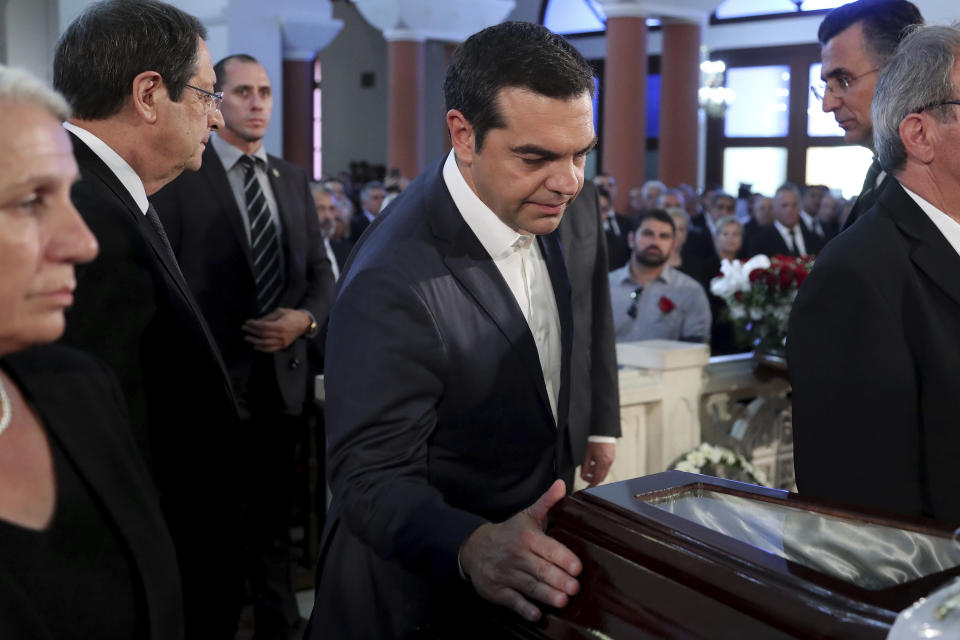Greece's Prime minister Alexis Tsipras touches the coffin of the former Cyprus' President Dimitris Christofias during his state funeral at the Orthodox Christian Church of the Lord's Wisdom in capital Nicosia, Cyprus, Tuesday, June 25, 2019. European communist and left-wing party heads and leaders from ethnically split Cyprus' breakaway Turkish Cypriot community were among those attending a funeral service for the country's former president Christofias. (AP Photo/Petros Karadjias)