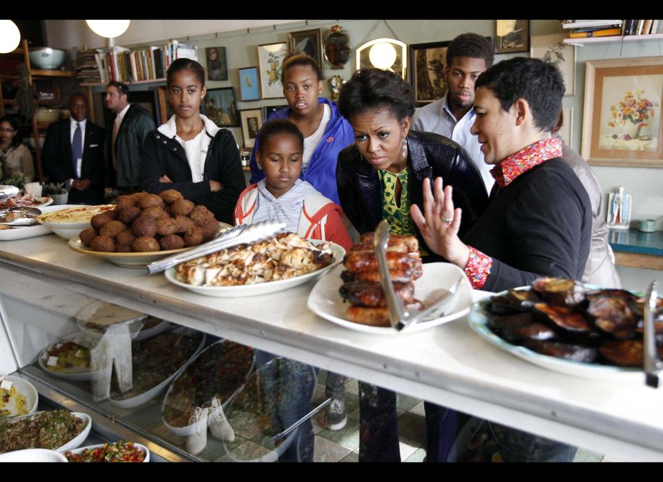 U.S. first lady Michelle Obama (C) stands with Karen Dudley (R), at her restaurant 'The Kitchen' as she makes an unscheduled stop for lunch in Cape Town, South Africa, on June 23, 2011. Founded in 1867 as a mixed community of freed slaves, merchants, and immigrants, the apartheid government in 1965 declared it 'white' and forcibly removed 60,000 residents and bulldozed their homes.  US First Lady Michelle Obama kicks off the last leg of her South African tour in Cape Town today, when she will meet with Nobel Peace Prize laureate Desmond Tutu. AFP PHOTO / AP / Charles Dharapak / POOL (Photo credit should read CHARLES DHARAPAK/AFP/Getty Images)