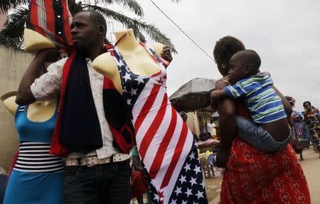 A street vendor holds a mannequin wearing a dress depicting the U.S. national flag in the streets of Abidjan August 3, 2014. REUTERS/Luc Gnago