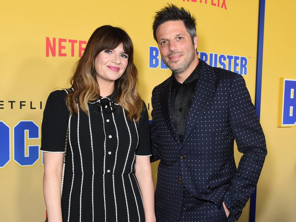 Casey Wilson, in a striped dress, poses with husband David Caspe during an event in 2022.