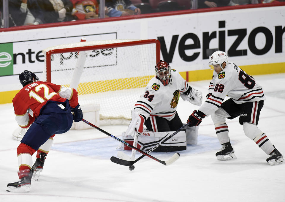 Chicago Blackhawks defenseman Caleb Jones (82) stops the puck in front of Blackhawks goaltender Petr Mrazek (34) and Florida Panthers center Eric Staal (12) during the first period of an NHL hockey game, Friday, March 10, 2023, in Sunrise, Fla. (AP Photo/Michael Laughlin)