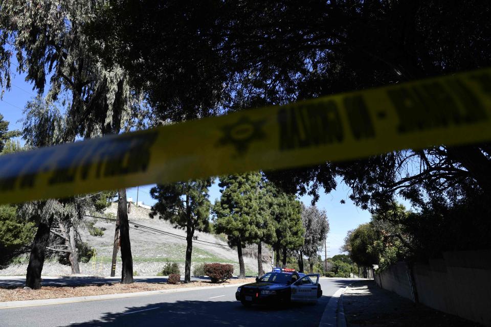 A police car and tape block a street in Rancho Palos Verdes, California, on Feb. 23, 2021, as police investigate a car accident involving golfer Tiger Woods, who was hospitalized Tuesday after a car crash in which his vehicle sustained "major damage," the Los Angeles County Sheriff's department said. Woods, the sole occupant, was removed from the wreckage by firefighters and paramedics, and suffered "multiple leg injuries," his agent said in a statement.