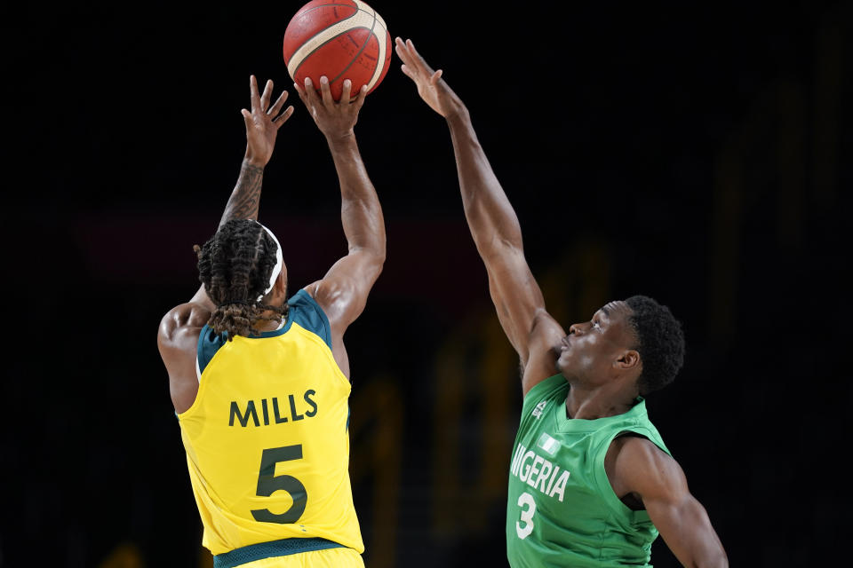 Nigeria's Caleb Agada (3) tries to block a shot by Australia's Patty Mills (5) during a men's basketball preliminary round game at the 2020 Summer Olympics, Sunday, July 25, 2021, in Saitama, Japan. (AP Photo/Charlie Neibergall)