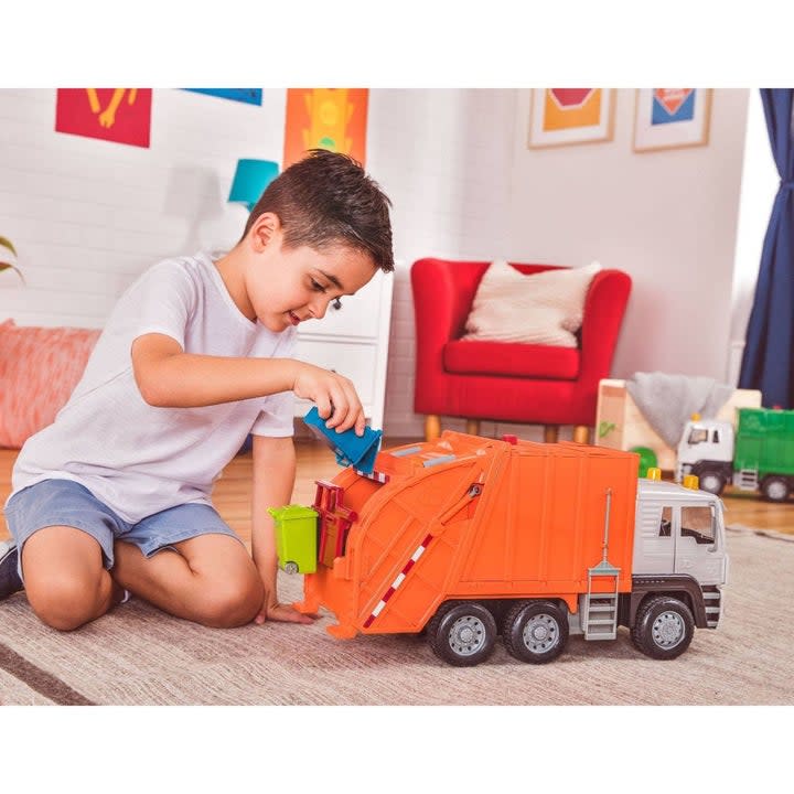 Kid playing with orange trash truck toy