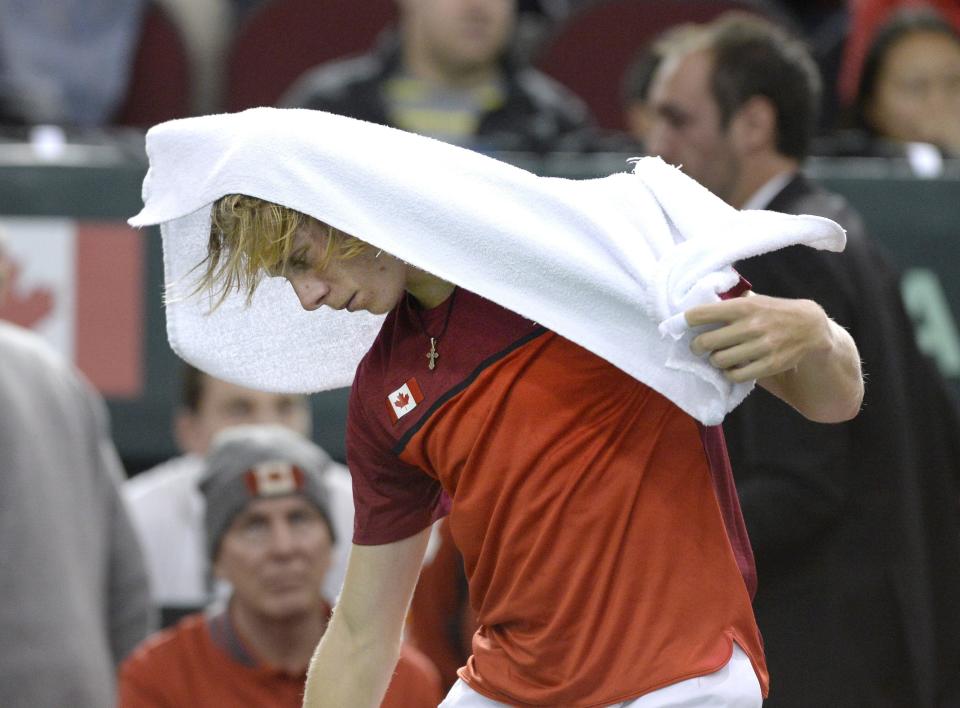 Canada's Denis Shapovalov covers his head with a towel as he leaves after a match was declared forfeited by umpire Arnaud Gabas, of France, after he was hit in the face with a ball during Davis Cup World Cup tie tennis action against Britain's Kyle Edmund, Sunday, Feb. 5, 2017, in Ottawa, Ontario. (Justin Tang/The Canadian Press via AP)