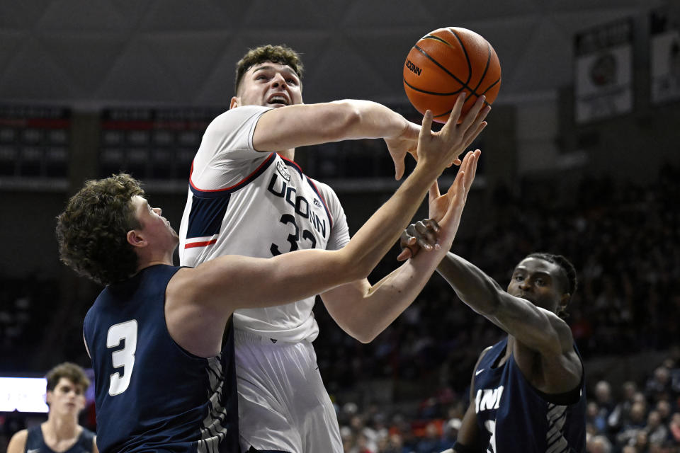 UConn center Donovan Clingan is fouled by New Hampshire forward Clarence Daniels as New Hampshire forward Jaxson Baker (3) defends in the first half of an NCAA college basketball game, Monday, Nov. 27, 2023, in Storrs, Conn. (AP Photo/Jessica Hill)