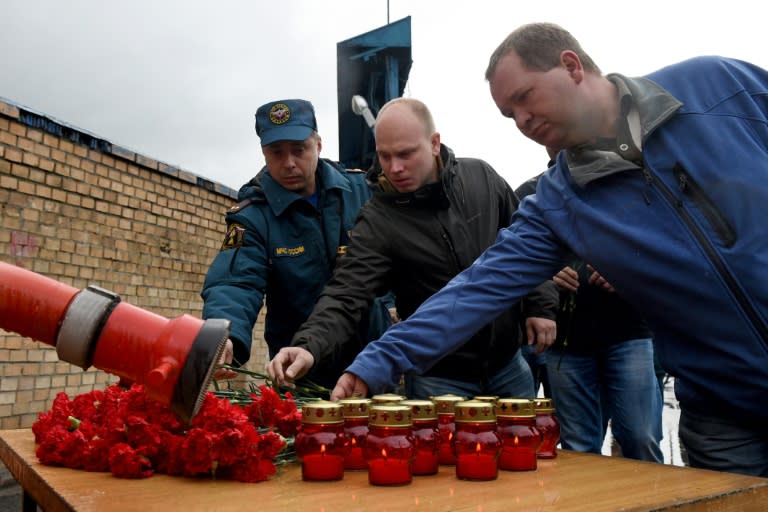 People place flowers and light candles in memory of eight firefighters killed at the site of a fire at a Moscow warehouse on September 23, 2016