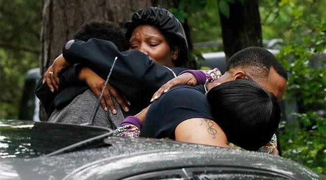 People embrace where several people were killed during a house-to-house shooting rampage. Photo: AP