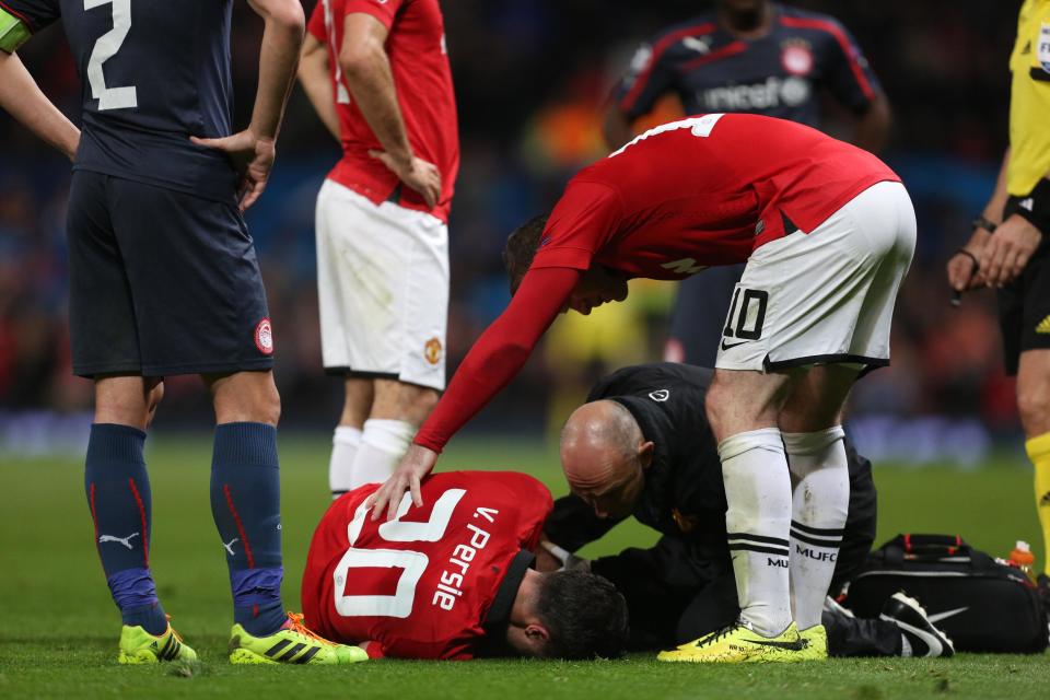 Manchester United's Robin van Persie, bottom, lies injured after colliding with Olympiakos's Kostas Manolas during their Champions League last 16 second leg soccer match at Old Trafford Stadium, Manchester, England, Wednesday, March 19, 2014. (AP Photo/Jon Super)