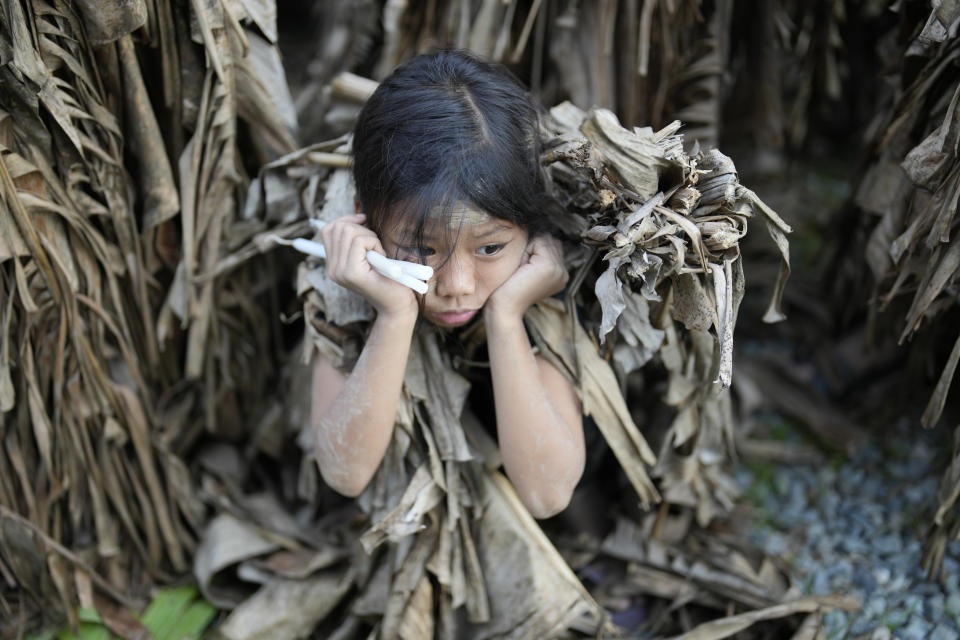 A young Catholic waits for the start of mass at the church of Saint John the Baptist during the mud festival at Bibiclat, Nueva Ecija province, northern Philippines, Monday, June 24, 2024. (AP Photo/Aaron Favila)