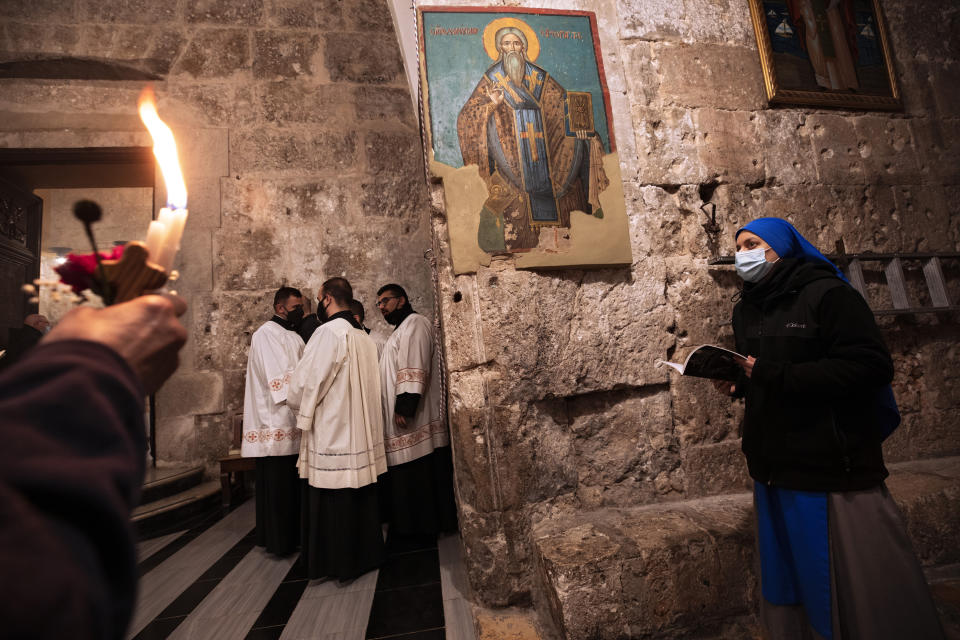 Priests and a nun wearing face masks attend Easter Sunday Mass at the Church of the Holy Sepulchre, where many Christians believe Jesus was crucified, buried and rose from the dead, in the Old City of Jerusalem, Sunday, April 4, 2021. (AP Photo/Oded Balilty)