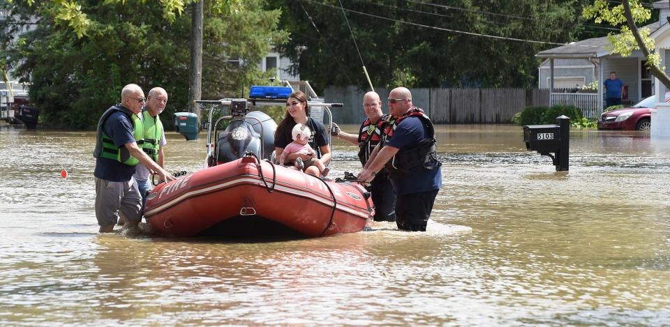 Kylie Barron of Monroe Township holds her baby boy, 8-month-old Orlando Obuch, as she was helped out of her flooding home on Plum Creek Drive in Evergreen Acres in Monroe Township in August by Capt. 2 Jack Richter and Chief Randy Howe (left) of the LaSalle Township Volunteer Fire Department and firefighter Scott Pancone and Capt. David Nadeau of the Monroe Township Fire Department.