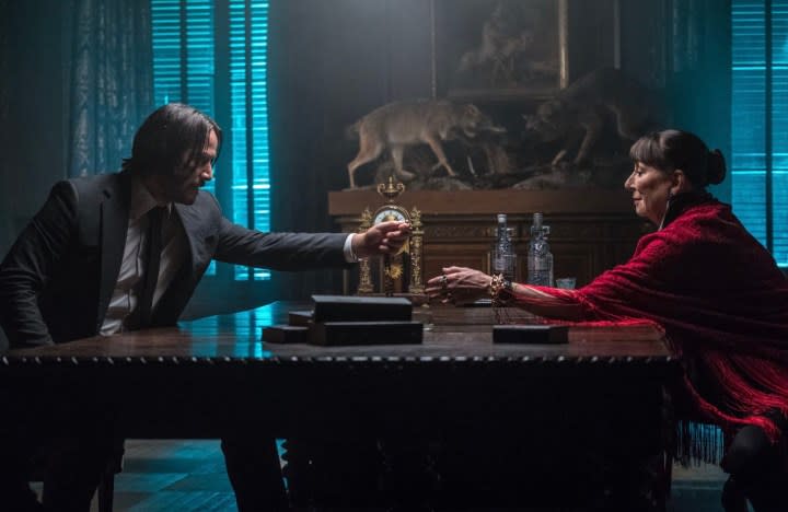 John Wick hands a cross to a woman in John Wick Chapter 3.