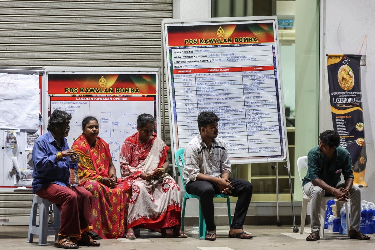 Relatives of an Indian woman who fell into an eight-meter-deep sinkhole wait for news near the accident site (EPA)