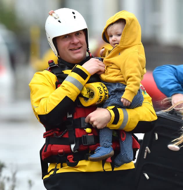 One-year-old Blake is carried by a rescue worker as emergency services continue to take families to safety, after flooding in Nantgarw, Wales, as Storm Dennis hit the UK.