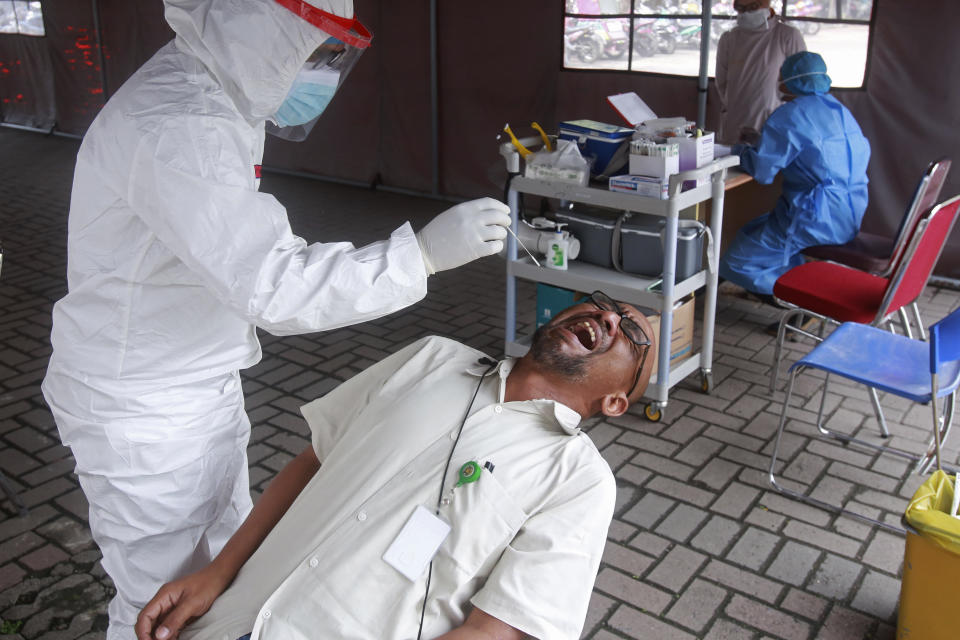 A man reacts as a medical worker collects his nasal swab sample to be tested for coronavirus, at North Sumatra University Hospital in Medan, North Sumatra, Indonesia, Thursday, Oct. 28, 2021. Indonesians are looking ahead warily toward the upcoming holiday travel season, anxious for critical tourist spending but at the same time worried that an influx of millions of visitors could lead to a new coronavirus wave just as the pandemic seems to be getting better. (AP Photo/Binsar Bakkara)